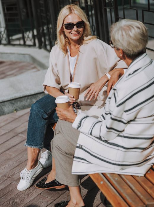 Two women enjoying coffee together outdoors near Rowe Residences.