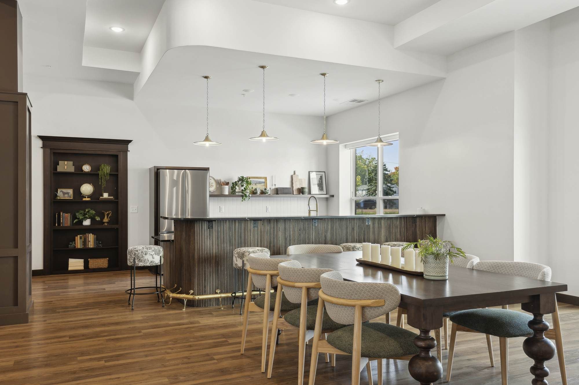 Spacious community lounge at Rowe Residences in Victoria, MN, featuring a large seating area, dining-style tables, and warm wood flooring.