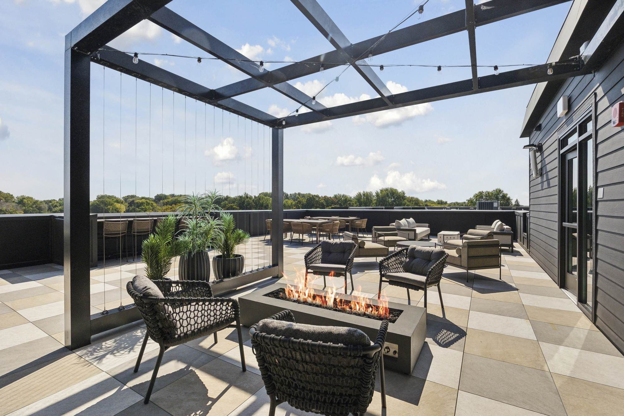 Rooftop lounge at Rowe Residences in Victoria, MN, featuring outdoor seating, a fire table, and open sky views.