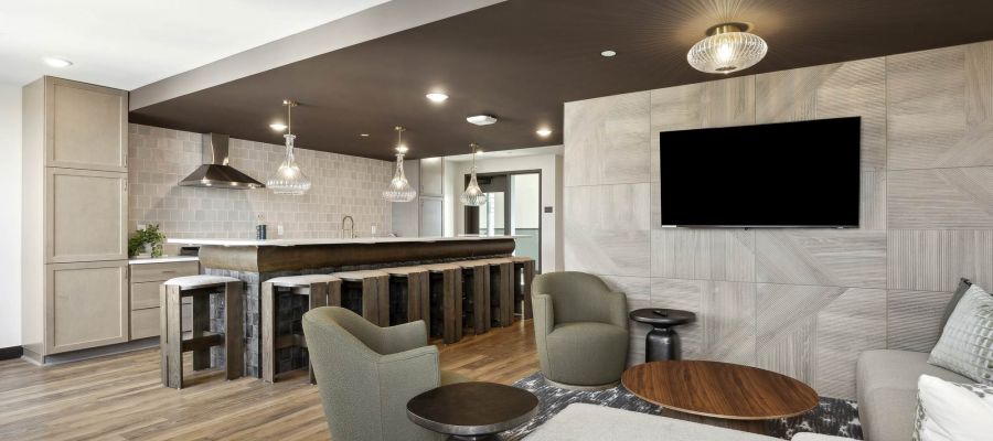 Modern community lounge at Rowe Residences featuring a kitchenette, bar seating, and comfortable gathering spaces.