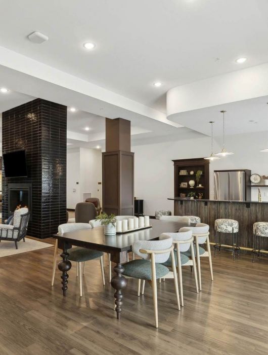 Spacious community lounge at Rowe Residences in Victoria, MN, featuring a large seating area, dining-style tables, and warm wood flooring.
