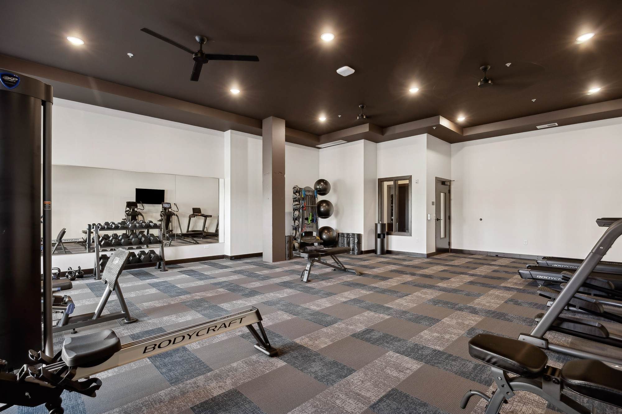 Fitness center at Rowe Residences in Victoria, MN, featuring free weights, strength-training equipment, and spacious workout areas.
