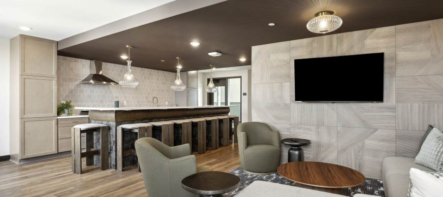 Modern community lounge at Rowe Residences featuring a kitchenette, bar seating, and comfortable gathering spaces.
