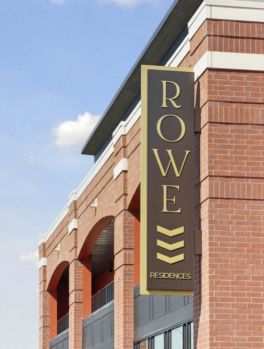 Exterior sign for Rowe Residences in Victoria, MN, mounted on a brick building with architectural arches.